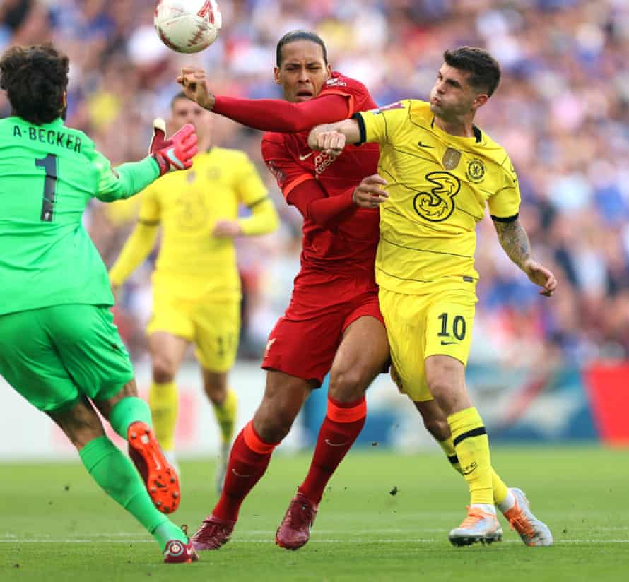 Virgil van Dijk of Liverpool fends off Christian Pulisic of Chelsea as Liverpool goalkeeper Alisson goes out to collect the ball.