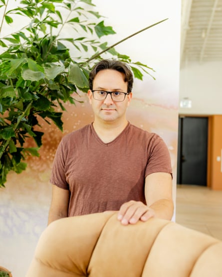 Kaplan stands behind a heavily cushioned chair next to a large houseplant