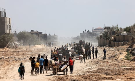 Palestinians pushing bikes and carts walk among debris from Rafah to Khan Younis