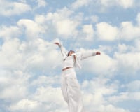 A woman spreads her arms in front of a cloudy sky
