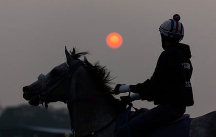 An exercise jockey and horse train at sunrise during a morning workout Wednesday before Saturday's 155th running of the Belmont Stakes at Belmont Park in Elmont, New York.