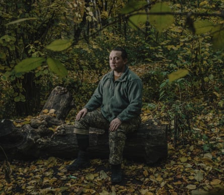 Lt Col Artem Kholodkevych sitting on a fallen tree trunk in a forest.