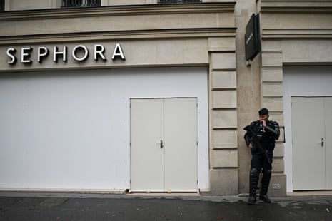 A police officer stands in front of a boarded-up Sephora store