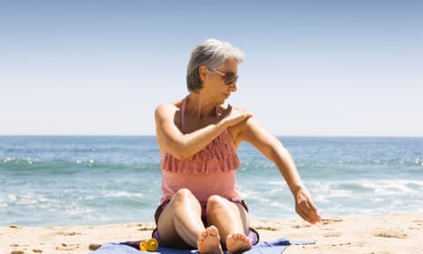 A woman on a beach applying sunscreen