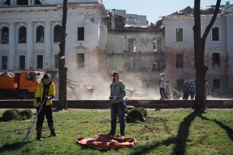 Locals remove the debris at the street damaged by rocket hits in Sumy, Ukraine.