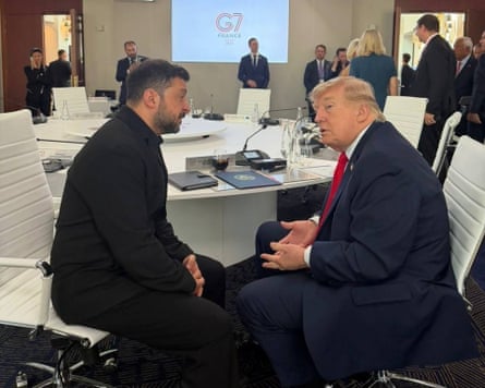 Zelenskyy and Trump sit on white leather chairs facing each other, very close, and appear to be having an earnest discussion.