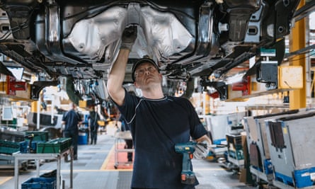 A worker inspecting the underside of a car at the JLR Halewood site