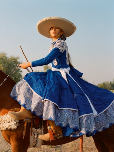 A woman in a blue traditional dress and hat riding side saddle