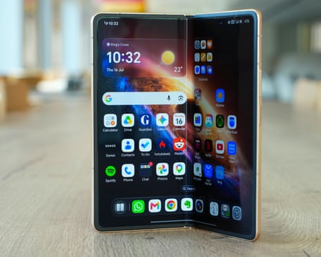 The Honor Magic V6 foldable smartphone stands partially open, displaying two screens with app icons and widgets.