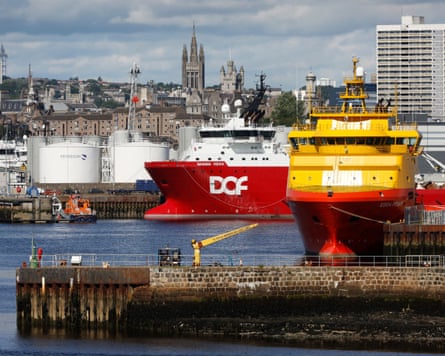 Large vessels docked in Aberdeen with the gas or oil storage tanks behind and the rest of city in the background