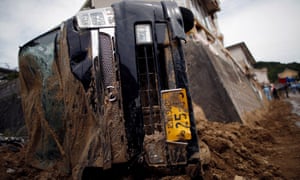 A car is left upturned after torrential rain caused a landslide in Kumano.