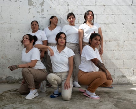 A group of seven women, three crouching in front, and four standing behind against a courtyard wall, pose for a photograph