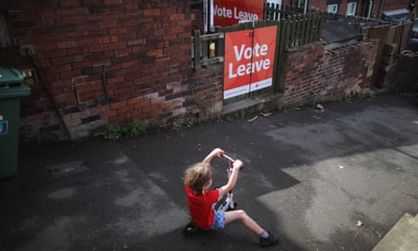 A young child rides a scooter past a 'Vote Leave' poster in the back alley in Batley, West Yorkshire