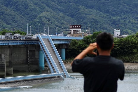 A person looks at a damaged bridge in Kumamoto.