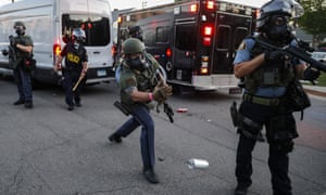 A police officer tosses a tear gas canister towards protestors on Hamline Avenue on Thursday.