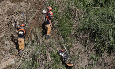 Rescuers use a line to transport a body recovered at the Itogon site where victims are believed to have been buried