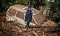 A girl stands next to a car partially buried in mud