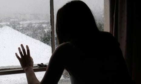 woman looking out of a window at snowy landscape