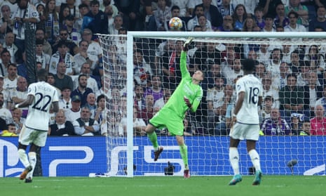 Real Madrid goalkeeper Andriy Lunin dives at a deflected shot from Bayern’s Alphonso Davies which goes over the cross bar.
