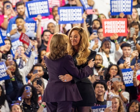 two women hugging as a crowd looks on, holding signs saying 'freedom'