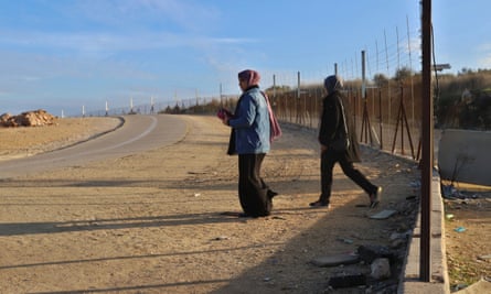 Palestinian women cross the broken separating barrier.