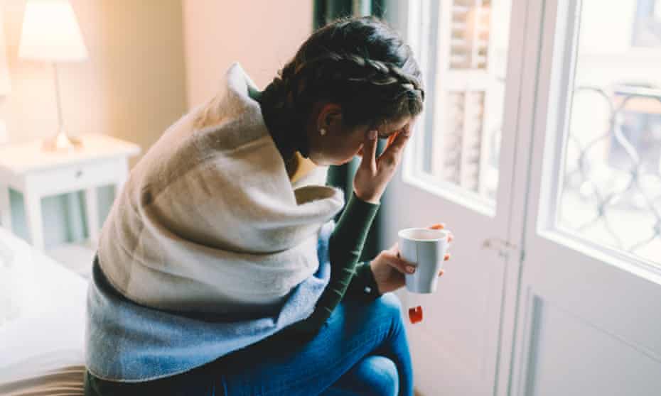 Woman with temperature staying home wrapped in scarf and drinking hot tea