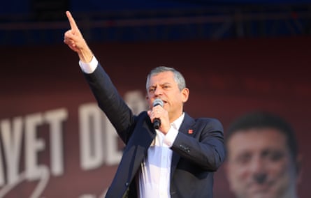 Özgür Özel points a finger in the air as he addresses the rally while holding a microphone