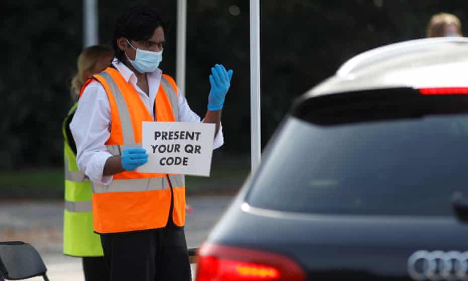 An NHS test-and-trace worker gestures to a driver at a test station in Richmond upon Thames.