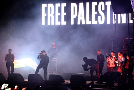 Kneecap performing in front of a ‘Free Palestine’ backdrop on stage