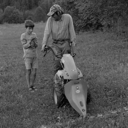 A black and white photo of a man and a boy with a small mower