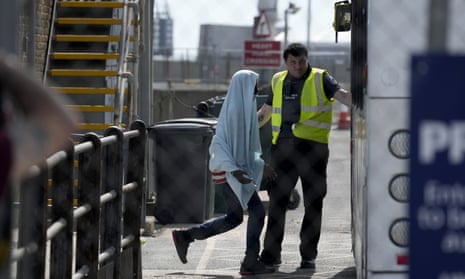 A man who undertook the crossing from France in a small boat is directed to board a transfer bus after disembarking from a British Border Force vessel in Dover in June 2022