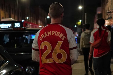 An Arsenal supporter with a shirt stating they are 'Champions'