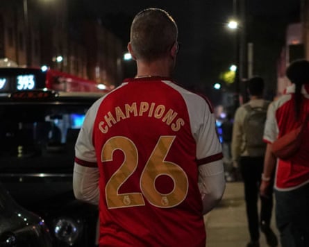 An Arsenal fan wears a football shirt embossed with the words ‘Champions 26’