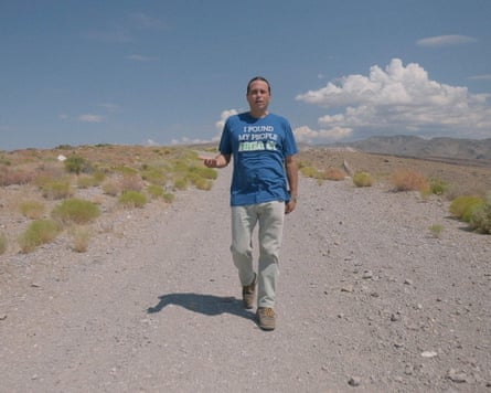 man in blue t-shirt walking through gravelly path outside
