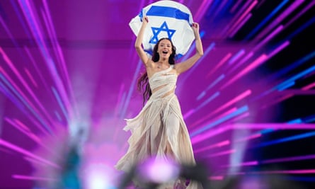 Eden Golan holds an Israeli flag above her head as she enters the arena
