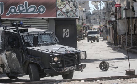 Armoured vehicles in dusty streets empty of people.