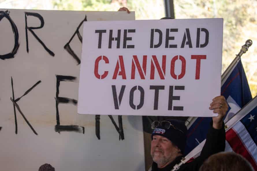 A man holds a sign reading "The dead cannot vote" at a rally in Alpharetta, Georgia.