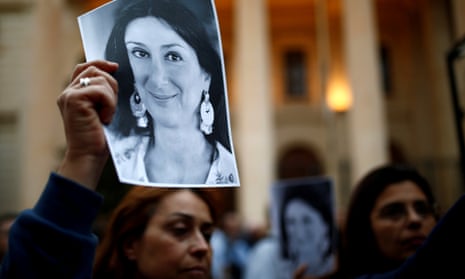 People hold up pictures of the assassinated journalist Daphne Caruana Galizia during a vigil and demonstration in Valletta, Malta