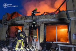 Firefighter use a hose to douse flames rising from the ruins of a shop