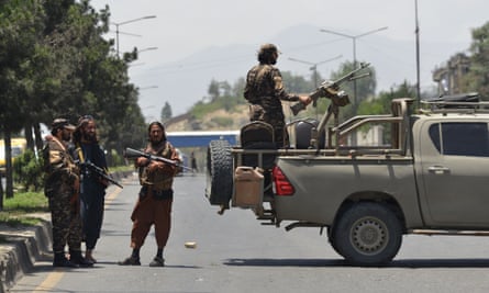 Taliban stand guard along a road in Kabul in June 2022