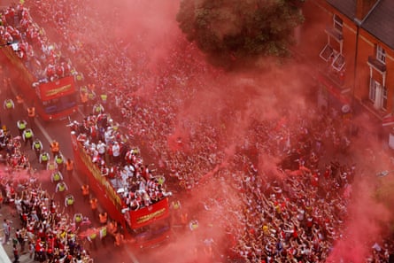Arsenal players and fans are enveloped in a red haze from flares during the street parade through north London on Sunday