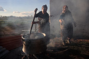 A woman stirs a large cauldron of food