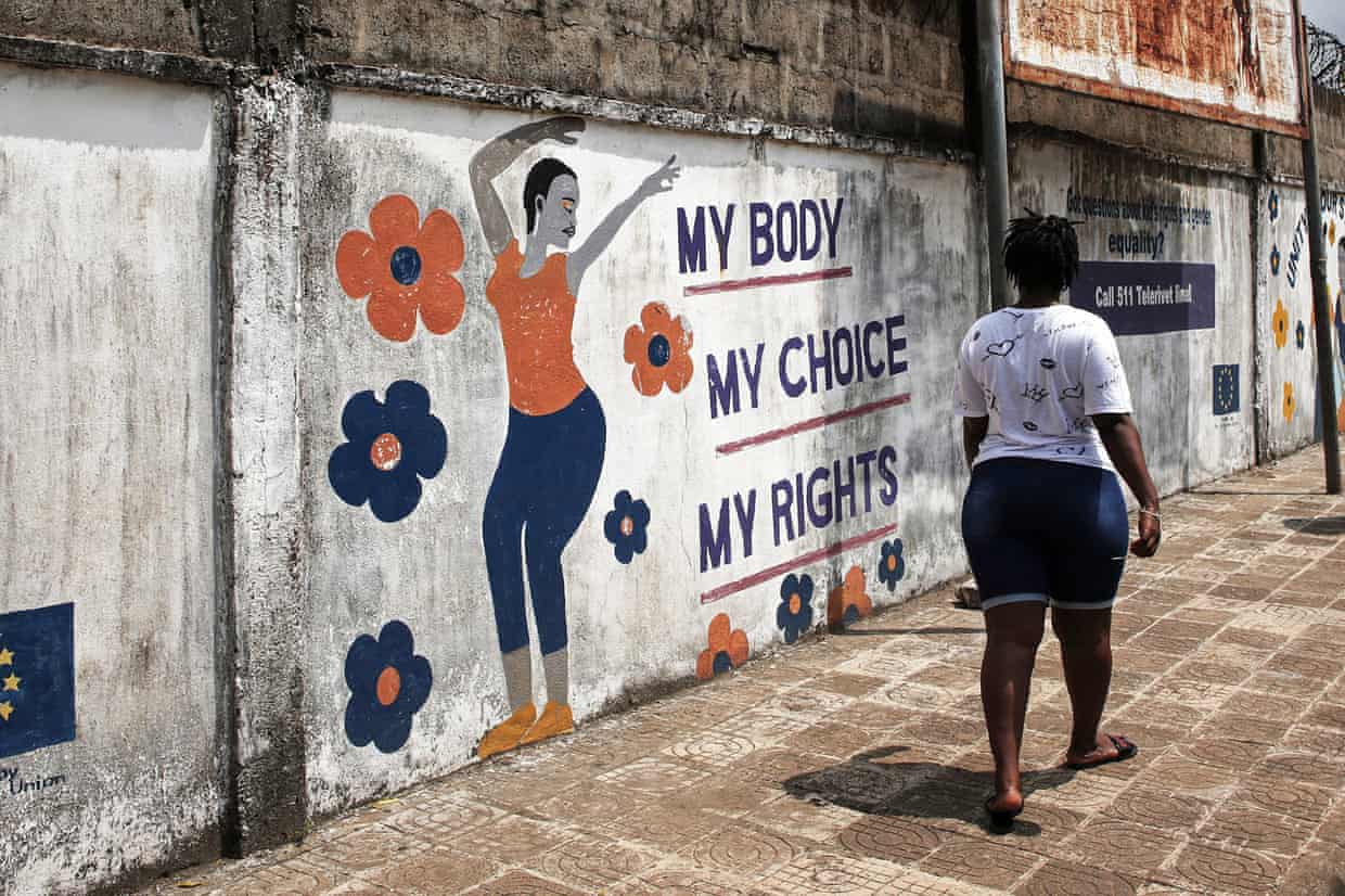 A woman walks past a mural with a painting of a woman and a slogan that reads ‘My Body, My Choice, My Rights’