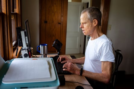 man in white t shirt sits at computer in side view