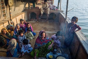 Women cautiously cook on an open fire on a boat. If the vessel were destroyed, the family would have to live on shore. A new boat costs about 1m rupees (£4,500)