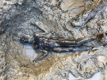 Well-preserved statue lying in mud.