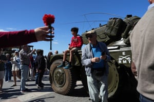 A child holding a red carnation sits on a military vehicle that took part in the 1974 revolution, on display in Lisbon’s Comercio square