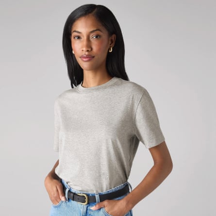 A model wears a light great T-shirt from With Nothing Underneath tucked into light blue jeans with a black belt and hands in pocket