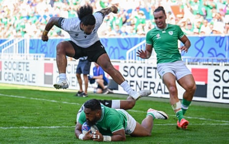 Bundee Aki of Ireland scores his side's fourth try despite the tackle of Hinckley Vaovasa of Romania.