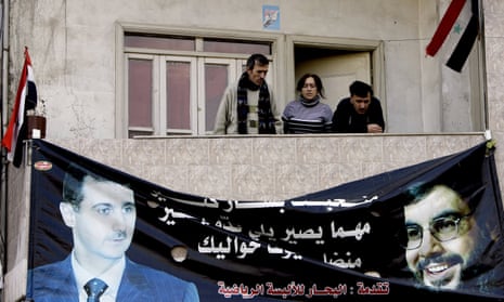Syrians stand above a poster of President Bashar al-Assad and Lebanese Hezbollah Leader Hassan Nasrallah in an Alawite neighbourhood in the western city of Homs in 2012